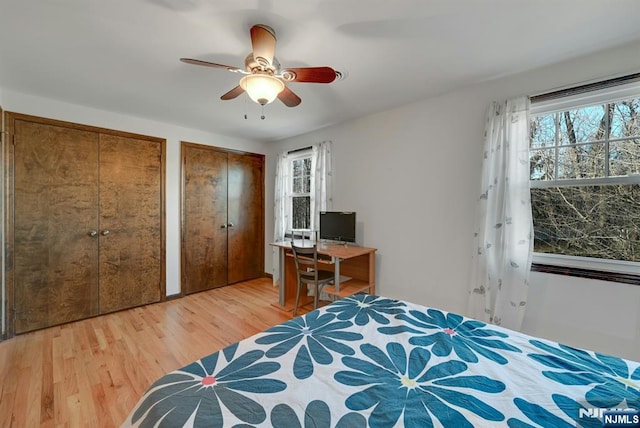 bedroom with light wood-type flooring, two closets, and a ceiling fan