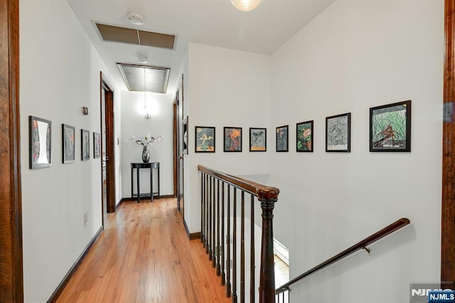 corridor featuring visible vents, baseboards, attic access, an upstairs landing, and light wood-style flooring