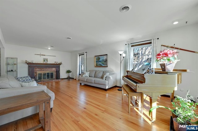 living area featuring a fireplace, visible vents, and light wood-type flooring