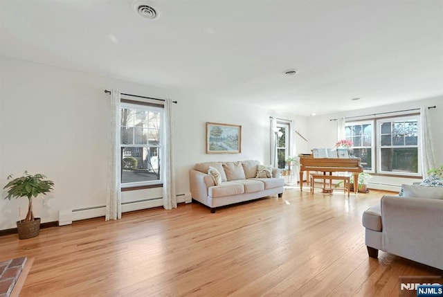 living area with baseboards, visible vents, baseboard heating, and light wood-type flooring