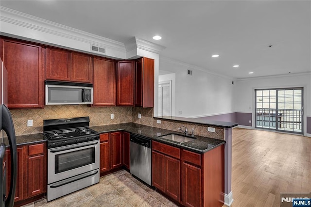 kitchen with a peninsula, appliances with stainless steel finishes, backsplash, and a sink