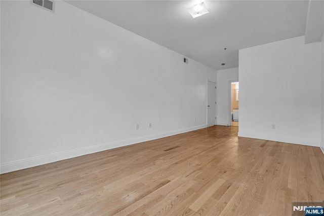 empty room featuring baseboards, visible vents, and light wood-style floors