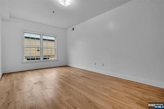 spare room with light wood-style floors, visible vents, and baseboards