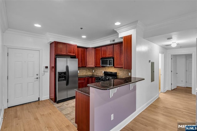 kitchen with reddish brown cabinets, tasteful backsplash, appliances with stainless steel finishes, dark stone countertops, and a peninsula