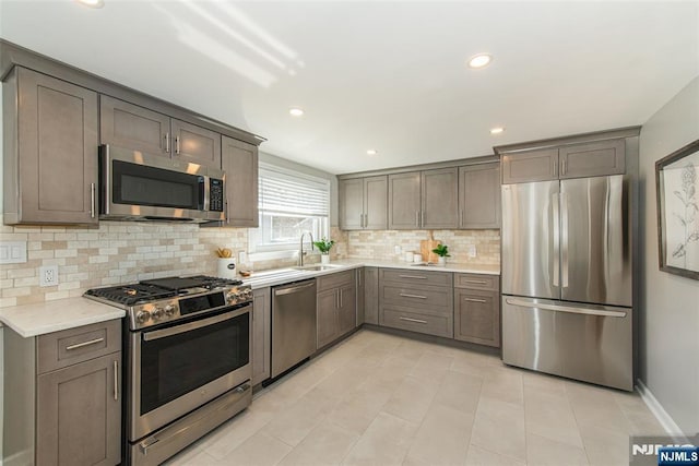 kitchen with recessed lighting, a sink, light countertops, appliances with stainless steel finishes, and backsplash