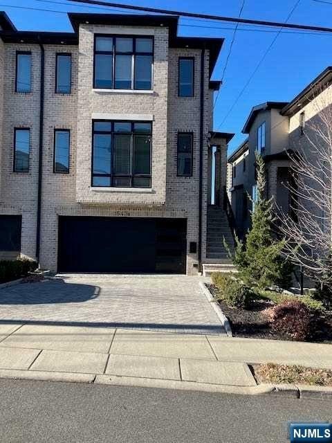 view of front facade with a garage, decorative driveway, and brick siding