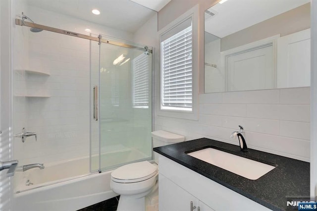 bathroom featuring visible vents, toilet, combined bath / shower with glass door, vanity, and backsplash