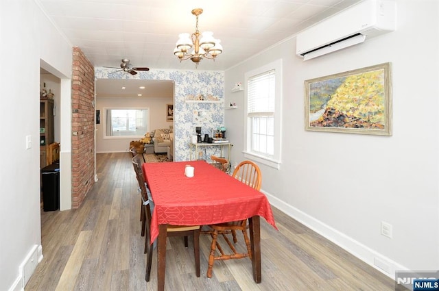 dining space featuring light wood-style floors, ornamental molding, baseboards, and a wall mounted AC