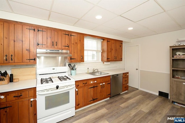 kitchen with dishwasher, gas range gas stove, brown cabinets, and under cabinet range hood