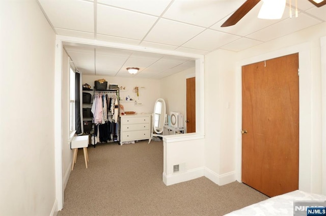 interior space with a ceiling fan, a paneled ceiling, visible vents, and baseboards