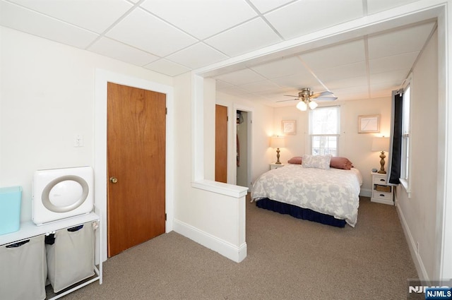 carpeted bedroom with a ceiling fan, a paneled ceiling, and baseboards