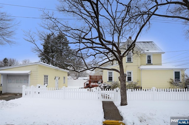 exterior space featuring a garage, fence private yard, a chimney, and an outbuilding