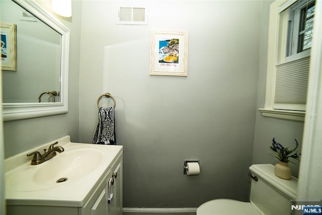 bathroom featuring toilet, baseboards, visible vents, and vanity