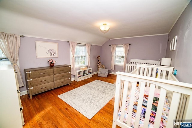 bedroom with baseboards, vaulted ceiling, and wood finished floors