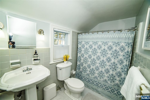 bathroom featuring toilet, shower / bath combo with shower curtain, tile walls, and tile patterned floors