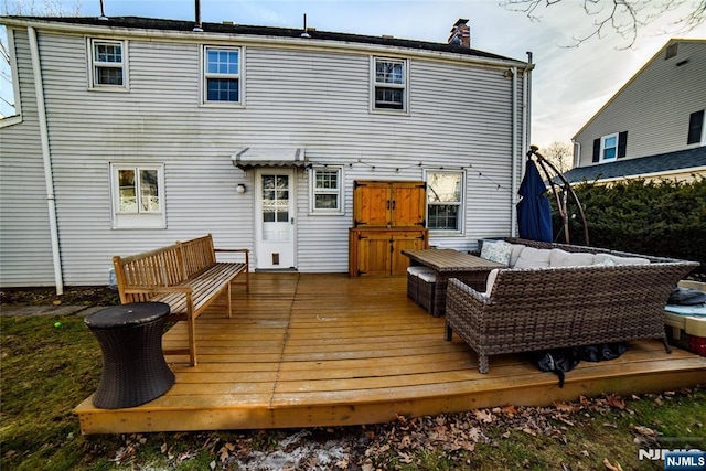 rear view of house with a deck, a chimney, and an outdoor living space