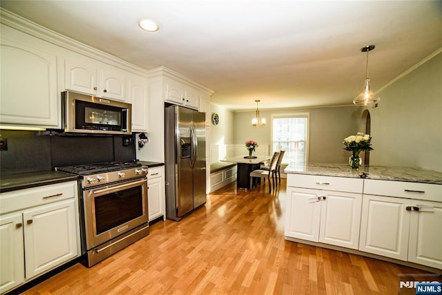 kitchen with white cabinets, hanging light fixtures, stainless steel appliances, crown molding, and light wood-style floors