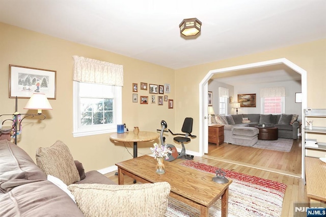 living room featuring arched walkways, wood finished floors, and baseboards