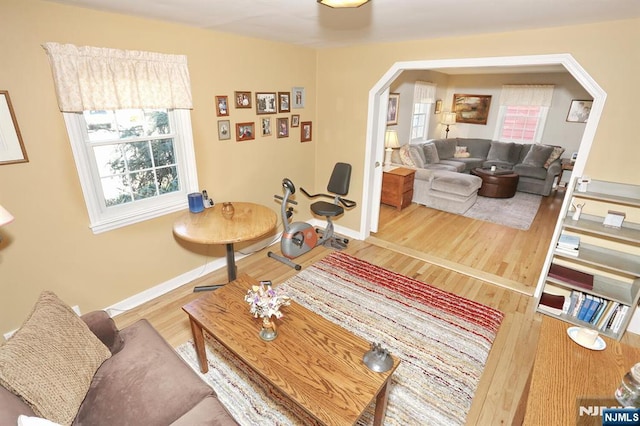 living area featuring baseboards, arched walkways, and wood finished floors