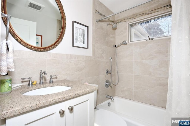 full bath with tile walls, shower / bath combination with curtain, visible vents, toilet, and vanity