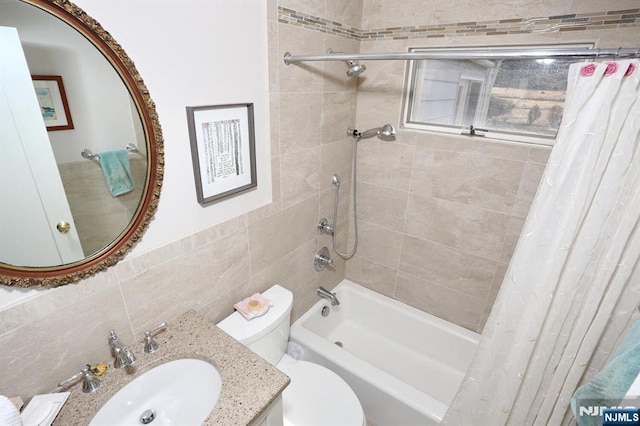 full bath with shower / bath combination with curtain, tile walls, vanity, and toilet