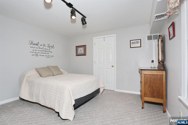 carpeted bedroom with baseboards, visible vents, and track lighting