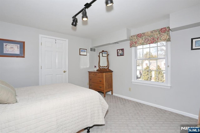 bedroom featuring track lighting, light colored carpet, visible vents, and baseboards