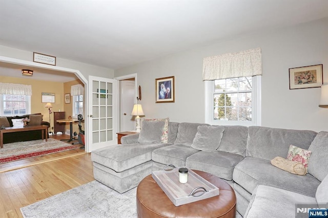 living room with arched walkways and wood finished floors