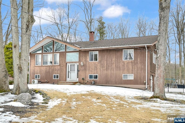 view of front of house with roof with shingles, fence, and a chimney