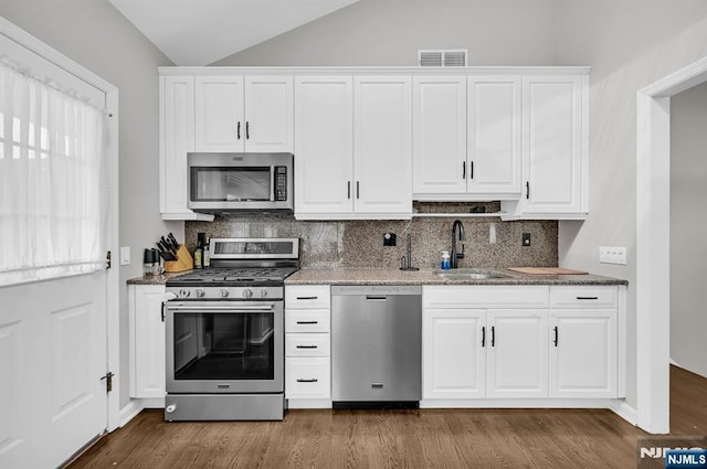 kitchen featuring visible vents, appliances with stainless steel finishes, white cabinets, and a sink