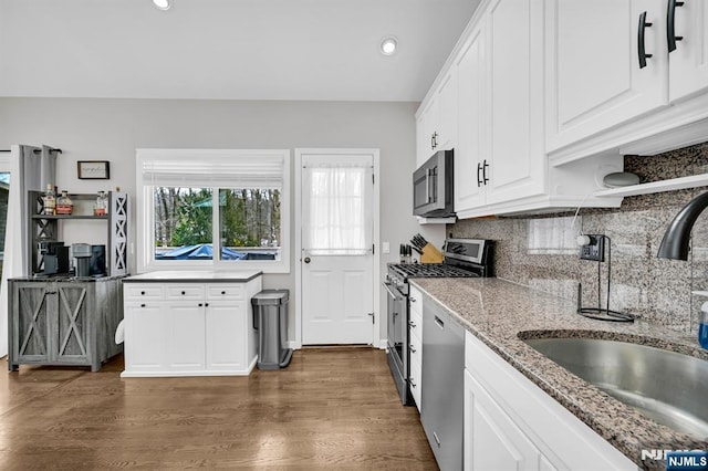 kitchen featuring stainless steel appliances, a sink, white cabinets, tasteful backsplash, and dark wood finished floors