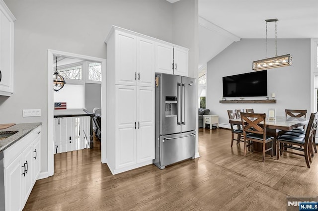 kitchen with dark wood-style flooring, appliances with stainless steel finishes, stone countertops, white cabinetry, and beamed ceiling