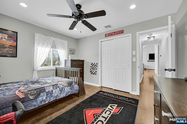 bedroom with baseboards, visible vents, wood finished floors, a closet, and recessed lighting