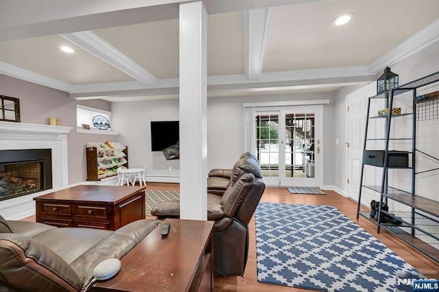 living room with beam ceiling, recessed lighting, ornamental molding, a glass covered fireplace, and wood finished floors