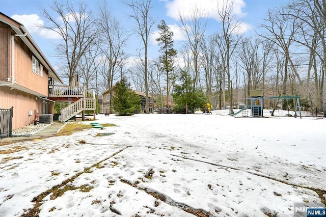 yard layered in snow featuring stairway, central AC unit, and a playground