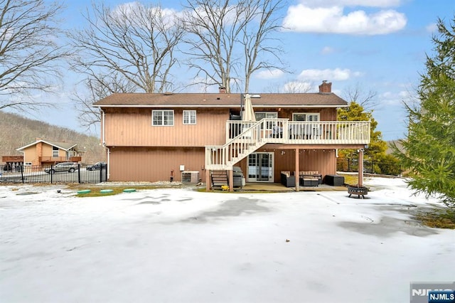 snow covered back of property with an outdoor living space with a fire pit, stairway, fence, cooling unit, and a wooden deck