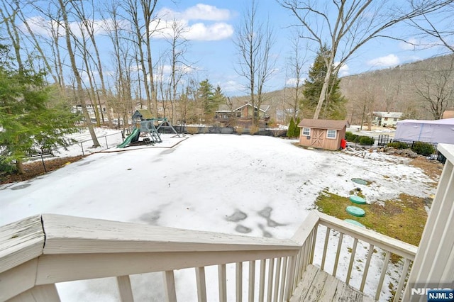 yard covered in snow with a shed, a playground, and an outdoor structure