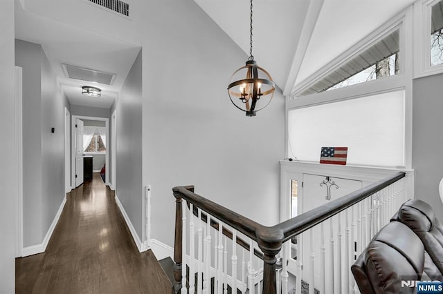 hall with visible vents, vaulted ceiling, an upstairs landing, wood finished floors, and baseboards