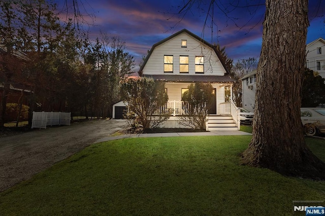 colonial inspired home with a porch, an outbuilding, a front lawn, and a gambrel roof