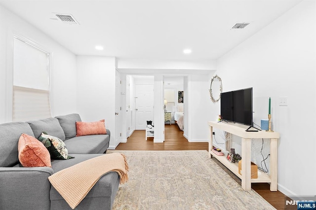 living room featuring wood finished floors, visible vents, and baseboards