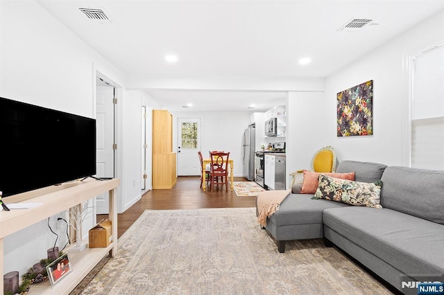 living area with recessed lighting, visible vents, and wood finished floors