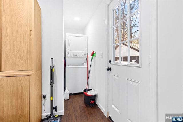 doorway featuring stacked washer / dryer, dark wood finished floors, and baseboards