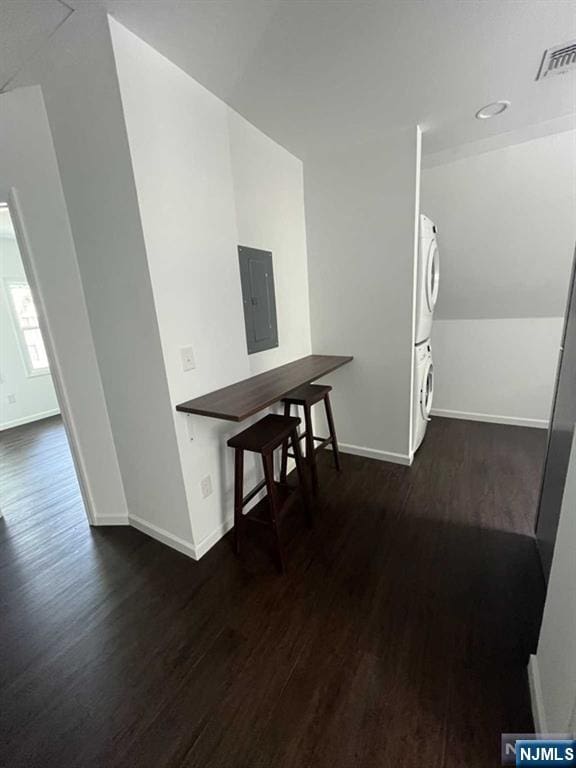 hall with dark wood-style floors, visible vents, stacked washer / dryer, vaulted ceiling, and electric panel