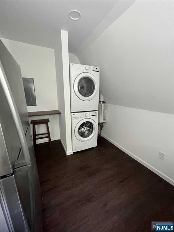 washroom featuring dark wood-style floors, laundry area, baseboards, and stacked washer / drying machine