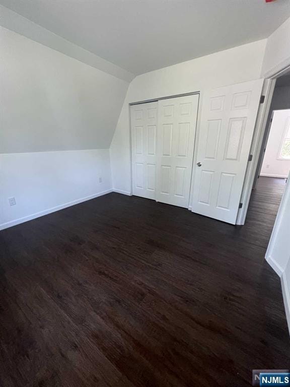 bonus room featuring vaulted ceiling, dark wood finished floors, and baseboards