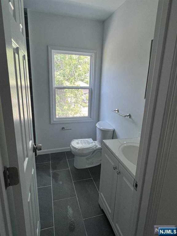 bathroom with tile patterned flooring, baseboards, vanity, and toilet