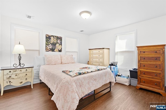 bedroom with dark wood-style floors and visible vents