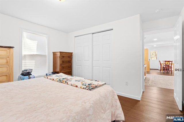 bedroom with a closet, dark wood finished floors, and baseboards