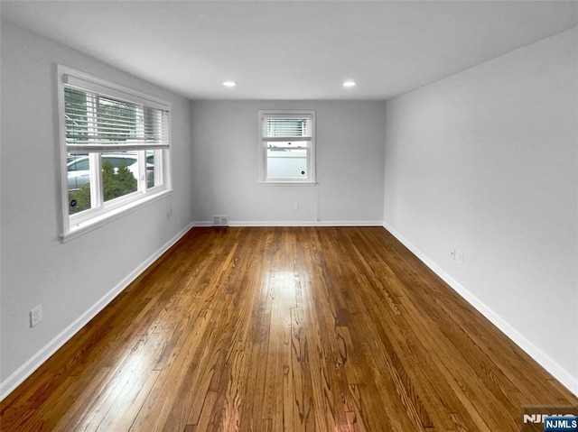 spare room with recessed lighting, wood-type flooring, visible vents, and baseboards