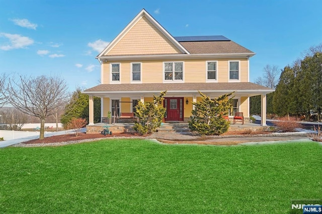 view of front of home with roof mounted solar panels, a porch, and a front yard